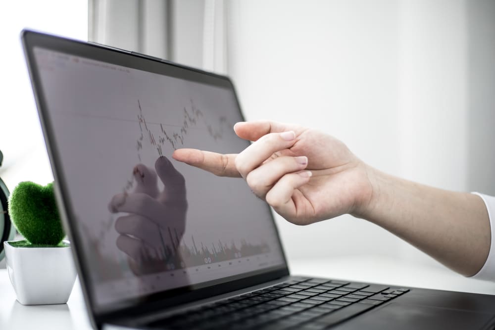 AStockInvestorIsPointingToALaptopScreenRunning