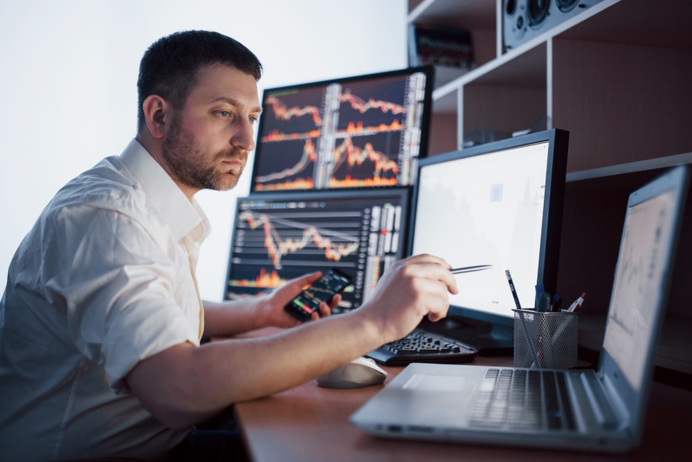 StockbrokerInShirtIsWorkingInAMonitoringRoomWith