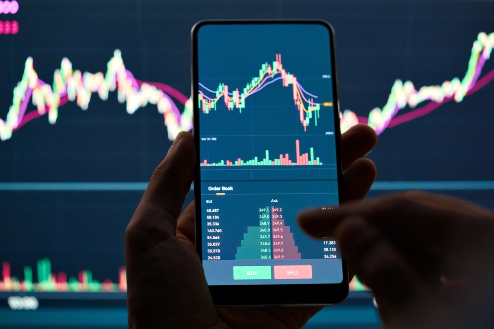 CryptoTraderInvestorBrokerHoldingFingerUsingCellPhoneApp