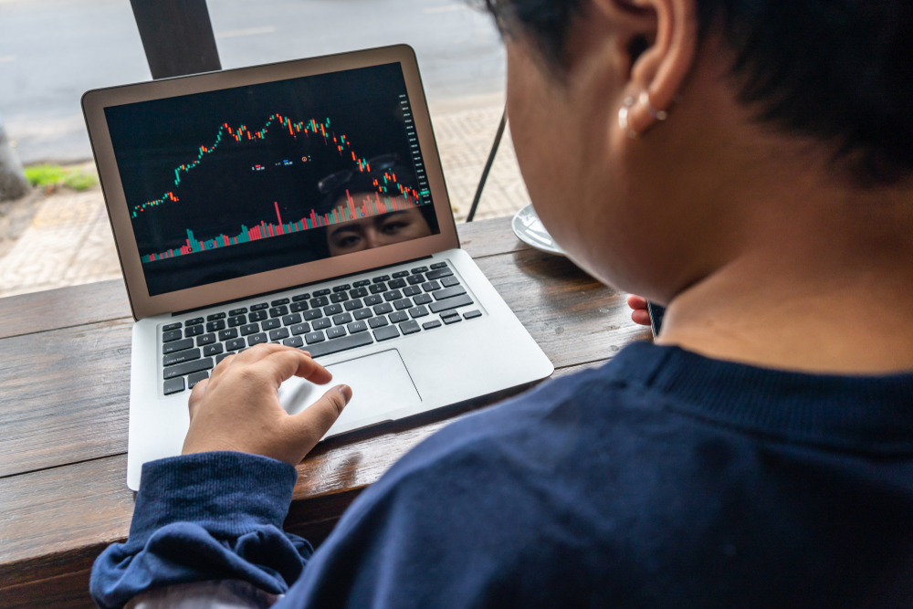 Rear,View,Of,Investor,Watching,Financial,Candlestick,Graph,On,Laptop